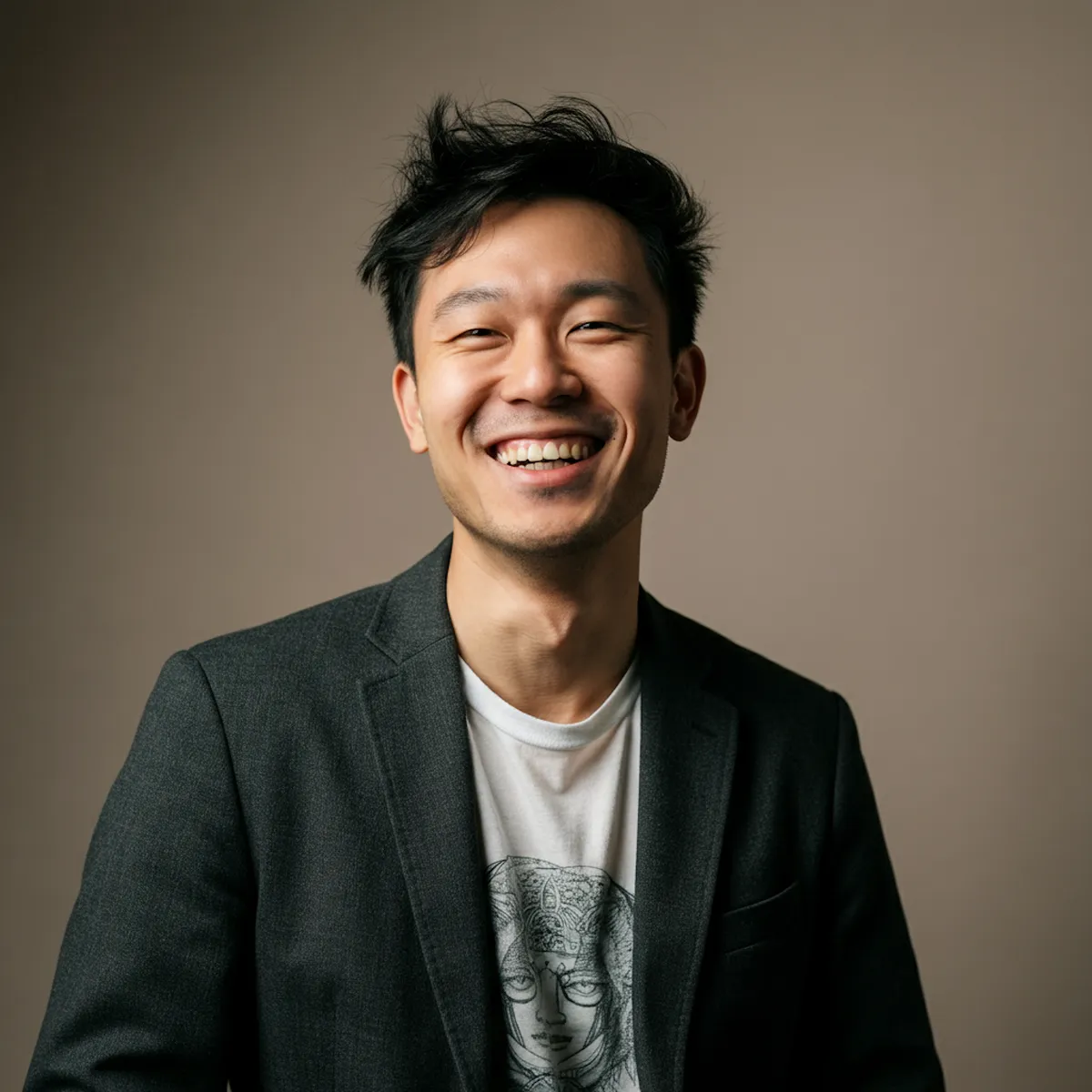 Portrait of a man smiling in casual gray sweater against dark background.